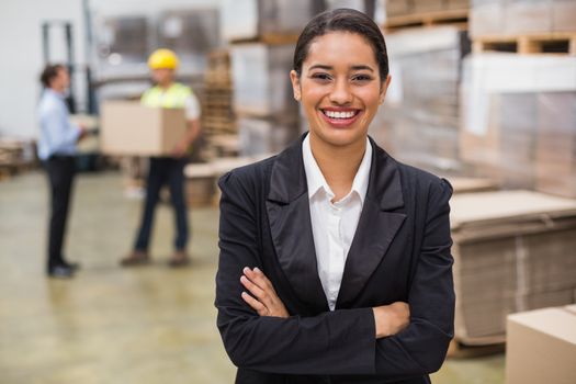 Portrait of smiling female manager with arms crossed in warehouse
