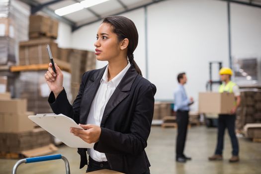 Pretty warehouse manager checking inventory in a large warehouse