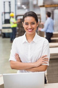 Portrait of smiling female manager with arms crossed in warehouse