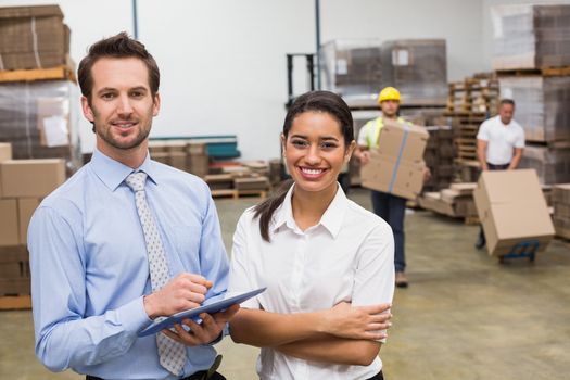 Smiling warehouse managers working together in a large warehouse