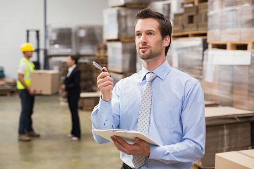 Warehouse manager checking his inventory in a large warehouse