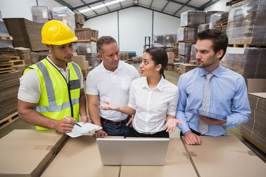 Warehouse managers and worker talking together in a large warehouse