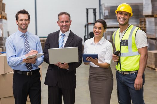 Smiling warehouse team working together in a large warehouse