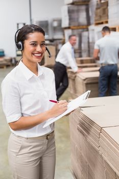 Warehouse manager writing on clipboard in warehouse