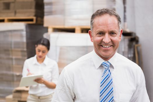 Warehouse manager smiling at camera in a large warehouse