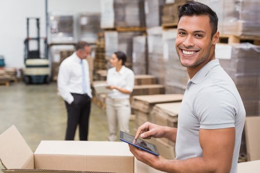 Smiling manager using digital tablet in warehouse