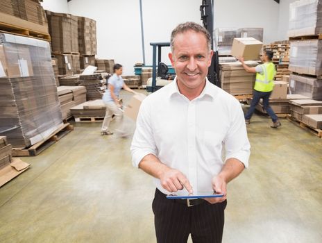 Manager using digital tablet during busy period in warehouse