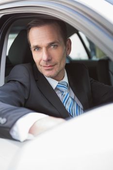 Happy businessman looking at camera in his car