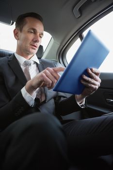 Handsome businessman using his tablet pc in his car