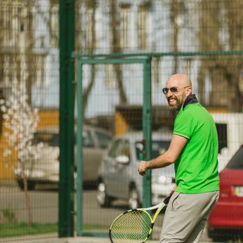 young man play tennis outdoor on tennis field at early morning