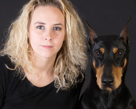 portrait of attractive woman and doberman pinscher dog on black background