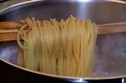 View in a saucepan with a wooden spoon hanging over the spaghetti.