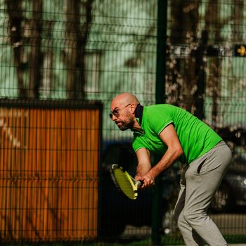 young man play tennis outdoor on tennis field at early morning