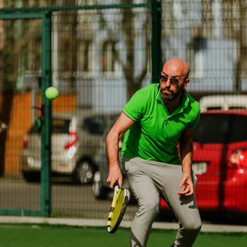 young man play tennis outdoor on tennis field at early morning