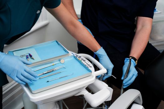Cropped image of dentist and assistant with tools tray