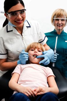 Dentist and assistant examining a little girl patient
