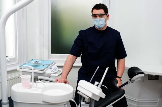 Male dental assistant standing beside chair