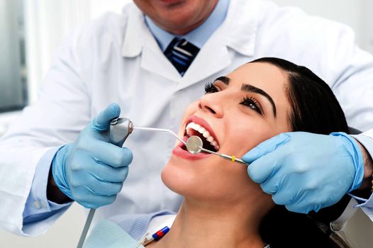 Male dentist whitening the woman teeth