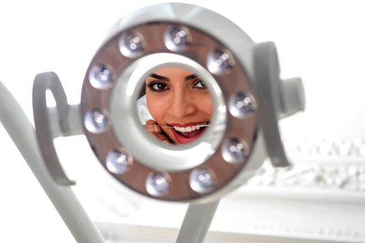 Woman flossing her teeth in front of light mirror