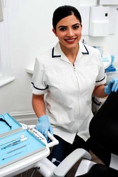 Female dental assistant sitting beside chair