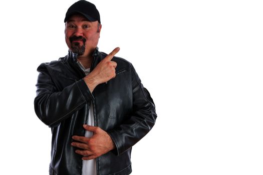 Jaunty trendy middle-aged man with a goatee wearing a grey leather jacket and cap pointing to blank copyspace for your advertising with a pleased expression, isolated on white