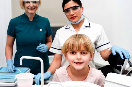 Female dental assistants with little girl patient