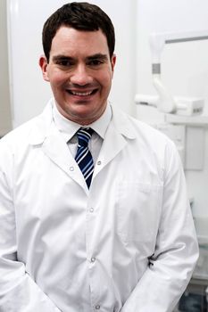 Happy male dentist posing at dental office