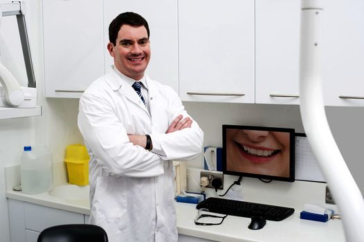 Happy dentist posing with computer screen