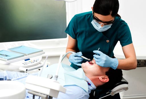 Female dentist treat male patient in clinic