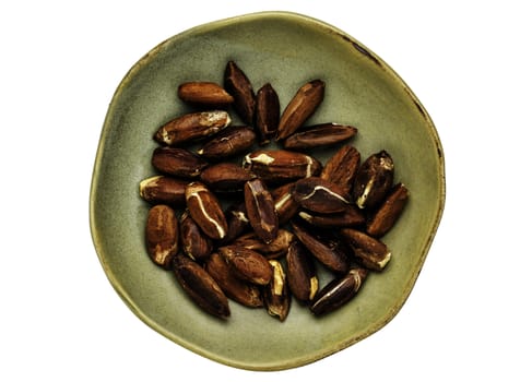 roasted pili nuts grown in Philippines, top view of ceramic bowl isolated on white