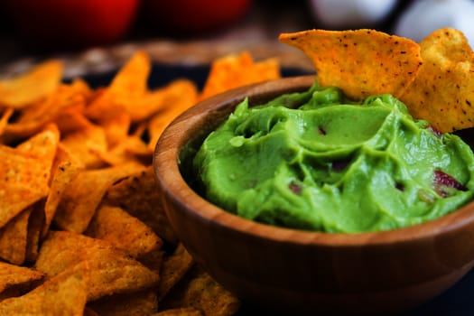 Guacamole in Wooden Bowl with Tortilla Chips Close Up