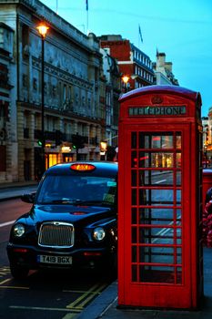 LONDON - APRIL 12: Famous red telephone booth and taxi cab on April 12, 2015 in London, UK. The red telephone box, a telephone kiosk for a public telephone designed by Sir Giles Gilbert Scott.