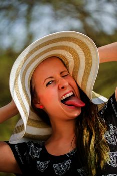 Portrait of grimace cheerful fashionable woman in stylish hat and frock. Crazy happy brunette girl with long hair in warm spring day