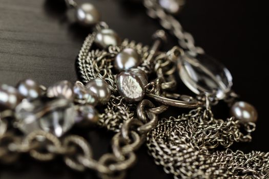 Assorted silver costume jewellery with a jumbled pile of chains with different shaped links, a clear crystal bead and a necklace of round silver beads with focus to the chains