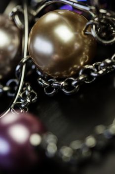 Close up of three attractive shiny purple beads attached by silver chains on an item of jewellery in a fashion and handicraft concept