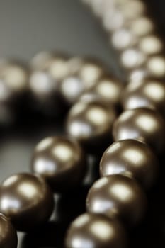 String of shiny grey beads winding through the frame in a close up view of fashion jewellery with selective focus to two beads