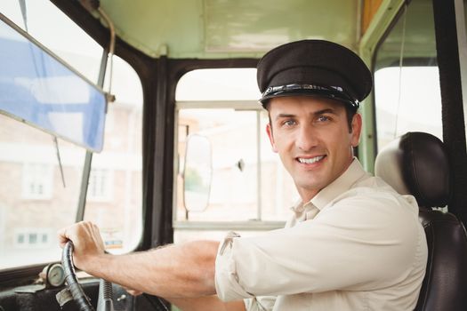 Smiling driver driving the school bus outside the elementary school