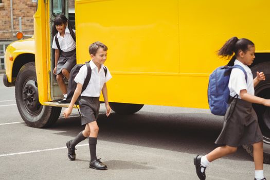 Cute schoolchildren getting off the school bus outside the elementary school