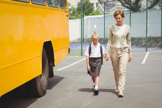 Mother walking her daughter to school bus outside the elementary school