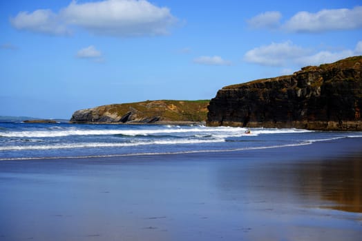 bright winter view of kayaker at ballybunion beach and cliffs on the wild atlantic way in ireland