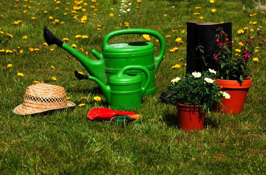 Gardening tools and a straw hat on the grass in the garden