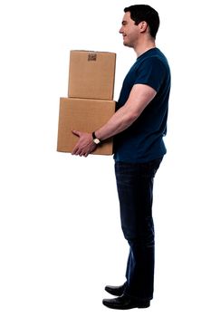 Sideways of casual man carrying stack of boxes
