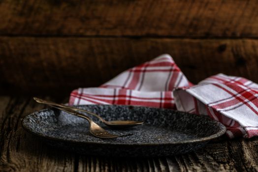 Antique plate and silverware photographed on a rustic wooded background.