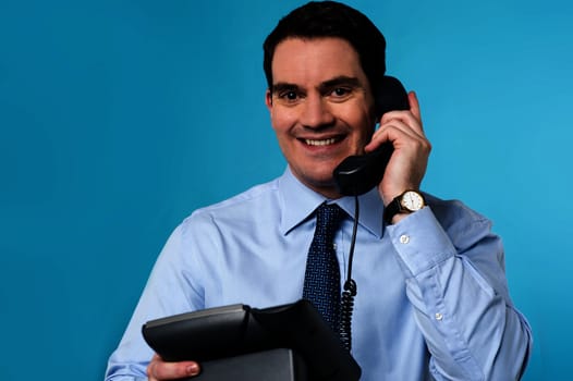 Happy male executive answering a phone call