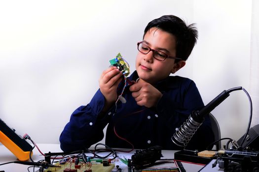 Young student performs experiments in electronics and dreams of the future.