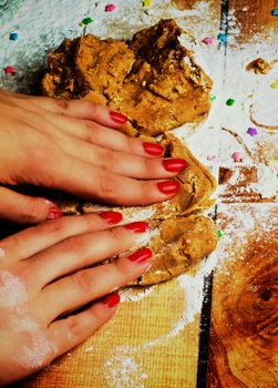 Hands of Women with Red Manicure Making Gingerbread Dough with Flour and Sweet Decoration closeup on Wooden background