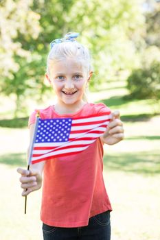Little girl waving american flag on a sunny day