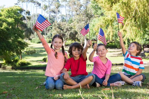 Happy little friends waving american flag on a sunny day