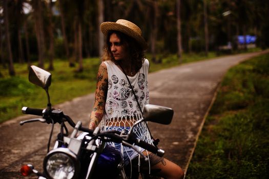 Tattoed girl sitting on blue motorcycle 