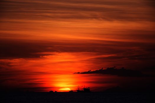 Sunset in Thailand with boat on horizon